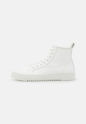 Baskets montantes en cuir blanc avec lacets à l'avant, semelle épaisse en caoutchouc et languette à l'arrière, vues de profil sur fond blanc.