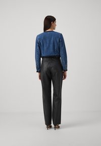 Jachetă din denim croită, cu mâneci lungi, de culoare albastră, cu tiv desfăcut. Pantaloni din piele neagră, cu talie înaltă, textură netedă, siluetă cu picioare largi.