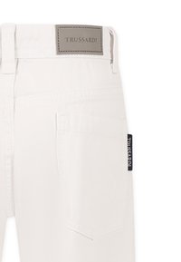 Pantaloni in denim bianco con una patch in pelle del logo Trussardi, dettagli di cucitura discreti e un'etichetta laterale con il nome del marchio.