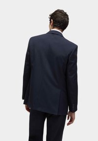 Marynarka w kolorze granatowym widziana z tyłu, z dopasowanym krojem, klapami i teksturowanym materiałem o subtelnym połysku.