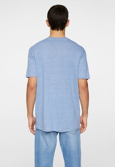 Camiseta de manga corta de color azul claro, hecha de una tela suave, con un cuello redondo y un corte relajado, vista desde la parte de atrás.