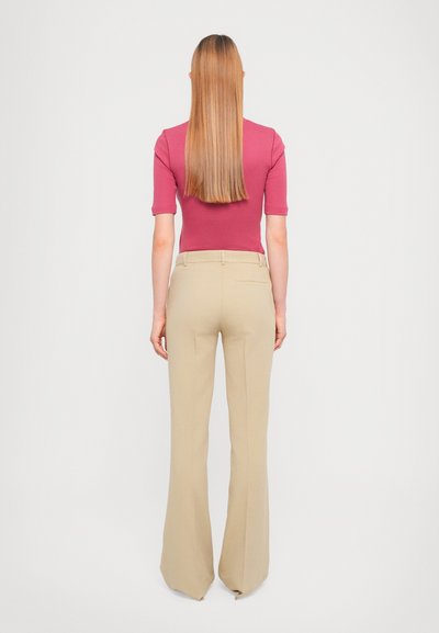 Top ajustado color marrón oscuro con mangas cortas, combinado con pantalones de pierna ancha color crema que cuentan con una textura suave y bolsillos traseros.