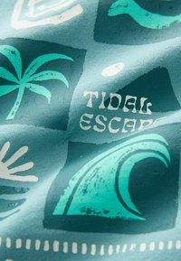 Tkanina s uzorkom koja sadrži palme i valove u tirkiznoj i bijeloj boji, s natpisom "TIDAL ESCAPE" u podebljanom, razigranom fontu.