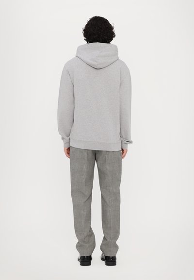 Grauer Kapuzenpullover mit lockerer Passform, kombiniert mit grauen karierten Hosen. Der Pullover verfügt über eine Kängurutasche und gerippte Bündchen.
