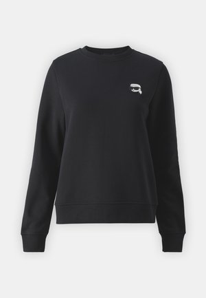 Sudadera negra hecha de tejido suave, con escote redondo, mangas largas y un pequeño diseño gráfico blanco en el pecho.