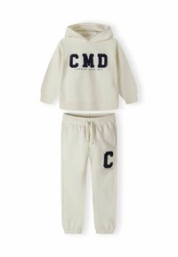 Cream-colored hoodie with "CMD" and "CAMDEN LOCK 1997" lettering in navy, paired with matching sweatpants featuring a "C" logo. Soft texture.