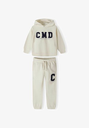 Krém színű kapucnis pulóver "CMD" és "CAMDEN LOCK 1997" téglalapban, navy színű felirattal, amelyhez párosított hasonló színű melegítőnadrág, amelyen "C" logó található. Puha tapintású.