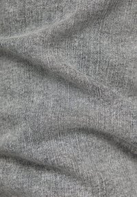 Close-up of gray fabric with fine silver sparkles and textured weave, showing soft folds and subtle shadows.