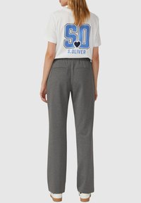 Weißes T-Shirt mit blauem "SO"-Grafik und "S.OLIVER"-Text, kombiniert mit grauen geraden Hosen mit lockerer Taille und Gesäßtaschen.