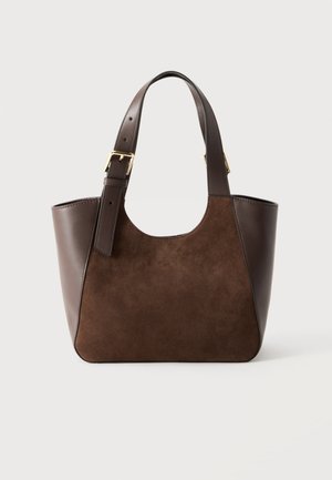 Borsa tote in pelle e camoscio marrone con tracolla regolabile con fibbia e ampia apertura superiore su sfondo chiaro.