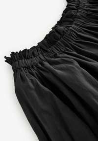 Zwarte gathered rok met een elastische tailleband, een gladde textuur en een vloeiende stof met zachte plooien overal.