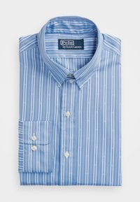 Ljusblå skjorta med knappar och vita vertikala ränder samt små fiskmönster. Har en klassisk krage och en bröstficka.