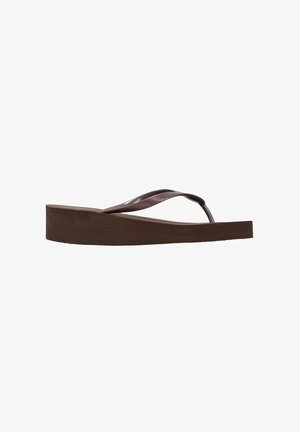 Chancla plana marrón con una suela gruesa y correas flexibles. Textura suave con un diseño minimalista, adecuada para uso casual.