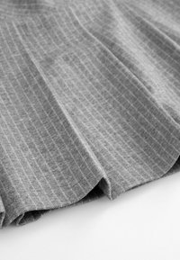 Szary materiał z pionowym wzorem w prążki, charakteryzujący się miękką teksturą i układem w fałdy, częściowo złożony na krawędzi.