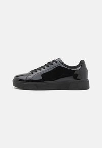 Schwarze Lackledersneaker mit runder Spitze, flacher Gummisohle und schwarzen Schnürsenkeln. Glatte, glänzende Textur auf der Oberfläche.