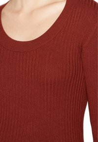 Sweter z prążkowanej dzianiny w kolorze spalanej pomarańczy z szerokim dekoltem w serek i dopasowanym krojem, prezentujący teksturowany materiał.