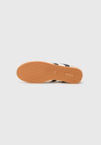Sneaker sole with a textured orange rubber outsole and black fabric straps. Features triangular patterns and a supportive grip design.