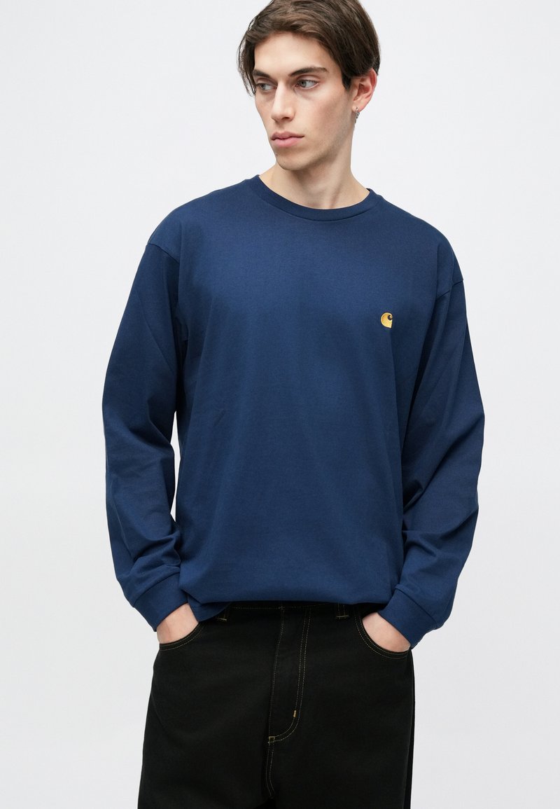 Mørkeblå langærmet t-shirt lavet af bomuld, med rund halsudskæring og et lille broderet logo på brystet. Glat tekstur.