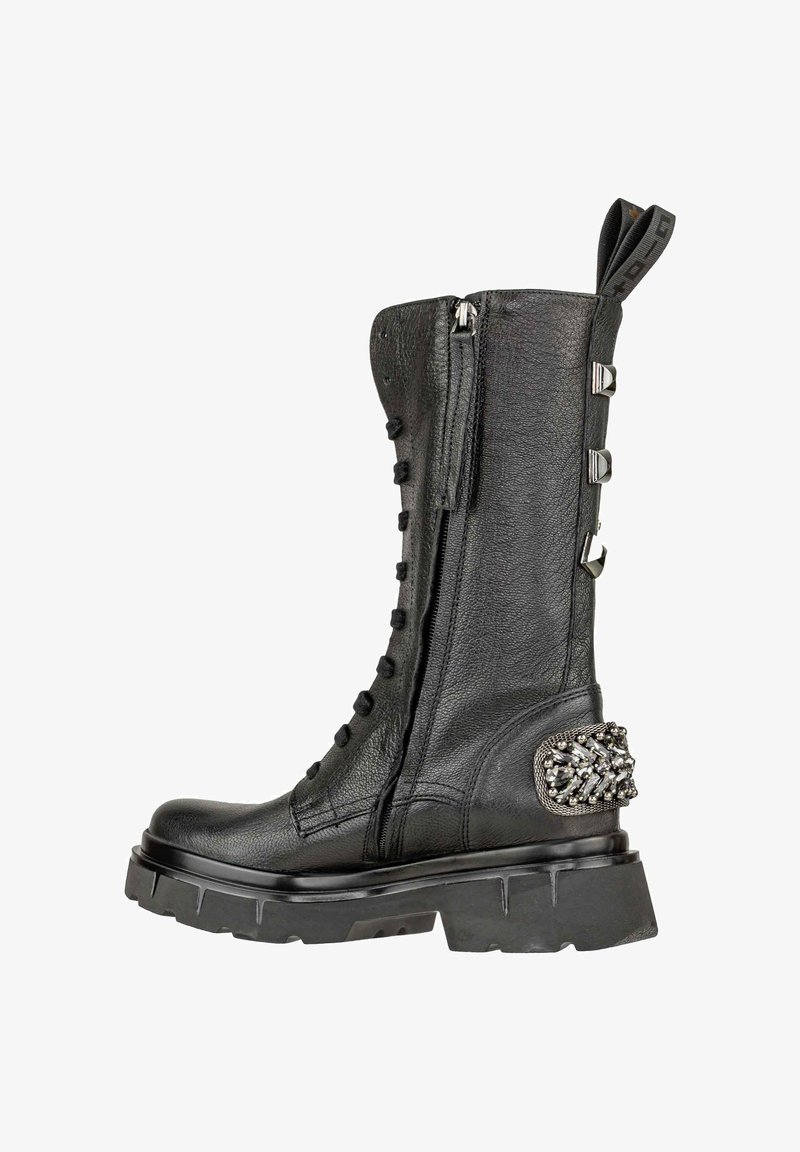 Stivale in pelle nera fino al polpaccio con cerniera laterale, lacci anteriori, suola spessa, borchie decorative sul tallone e un tassello per il sollevamento in cima.