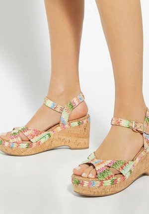 Sandales compensées avec des brides tissées colorées en rose, vert et bleu sur une semelle en liège, équipées d'une fermeture à boucle pour un maintien sécurisé.