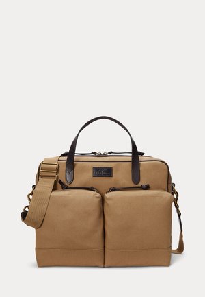 Geantă tip servietă din pânză de culoare bej, cu două buzunare frontale cu fermoar, mânere din piele maro închis și o curea ajustabilă pentru umăr cu accesorii din alamă.