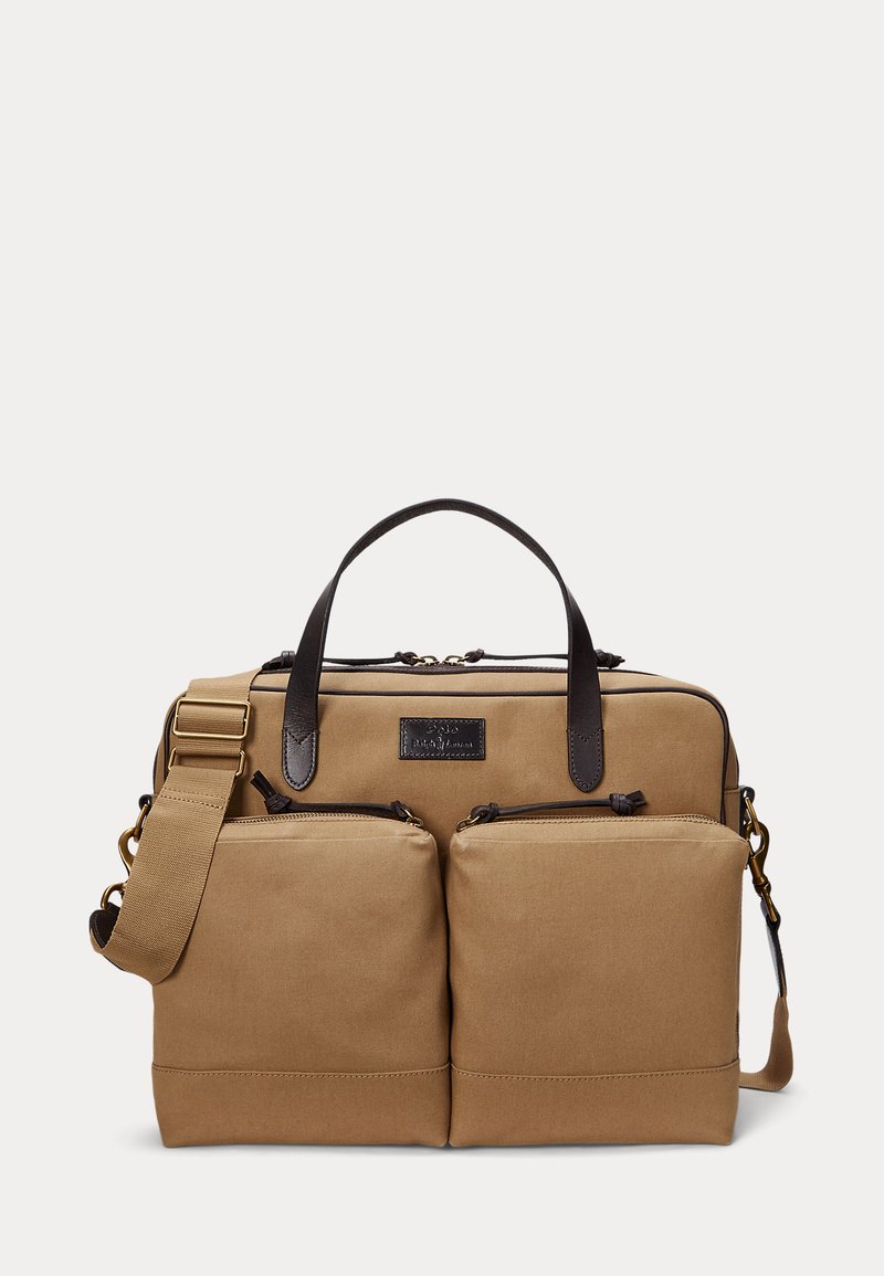 Tan canvas briefcase with two front zippered pockets, dark brown leather handles, and an adjustable shoulder strap with brass hardware.