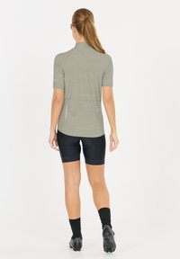 Maillot de cyclisme à manches courtes gris clair avec un design texturé, associé à un cuissard noir et des chaussettes noires. Affichant une coupe sportive.