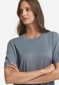 Ljusblå stickad t-shirt med rund halsringning och korta ärmar, med en mjuk textur och en något avslappnad passform.