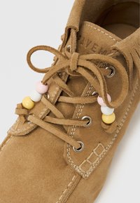 Καφέ γνήσιο δέρμα σουέντ παπούτσι με στρογγυλή μύτη, με κορδόνια και διακοσμητικές χάντρες σε ροζ, λευκό και κίτρινο στα κορδόνια.