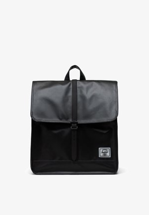 Mochila negra hecha de material duradero con solapa plegable, hebilla ajustable y un pequeño parche de marca en la parte frontal.