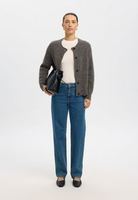 Šedý kardigan s kulatým výstřihem a knoflíky, krémové tričko, modré džíny s rovnými nohavicemi, černá kabelka a černé baleríny. Jemné textury, ležérní střih.