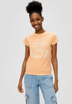 Perzikkleurig katoenen T-shirt met korte mouwen, voorzien van een witte vlinderafbeelding en tekst, gecombineerd met lichtblauwe cargobroeken.