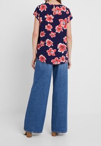 Květinový námořnický top s krátkými rukávy a detailem klíčové dírky na zádech, doplněný volnými světle modrými džíny a tanovými sandály na blokovém podpatku.