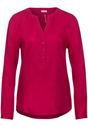 Blusa magenta de manga larga con escote redondo, cierre frontal parcial con botones y hombros ligeramente fruncidos.
