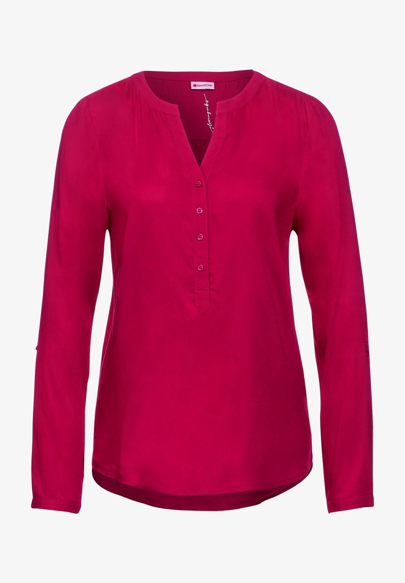 Blouse magenta à manches longues avec col rond, patte de boutonnage partielle à l'avant et épaules légèrement froncées.