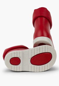 Botas de goma rojas con suela blanca, textura lisa y forma redondeada. Cuentan con un cuello acolchado para mayor comodidad y agarre en la parte inferior.