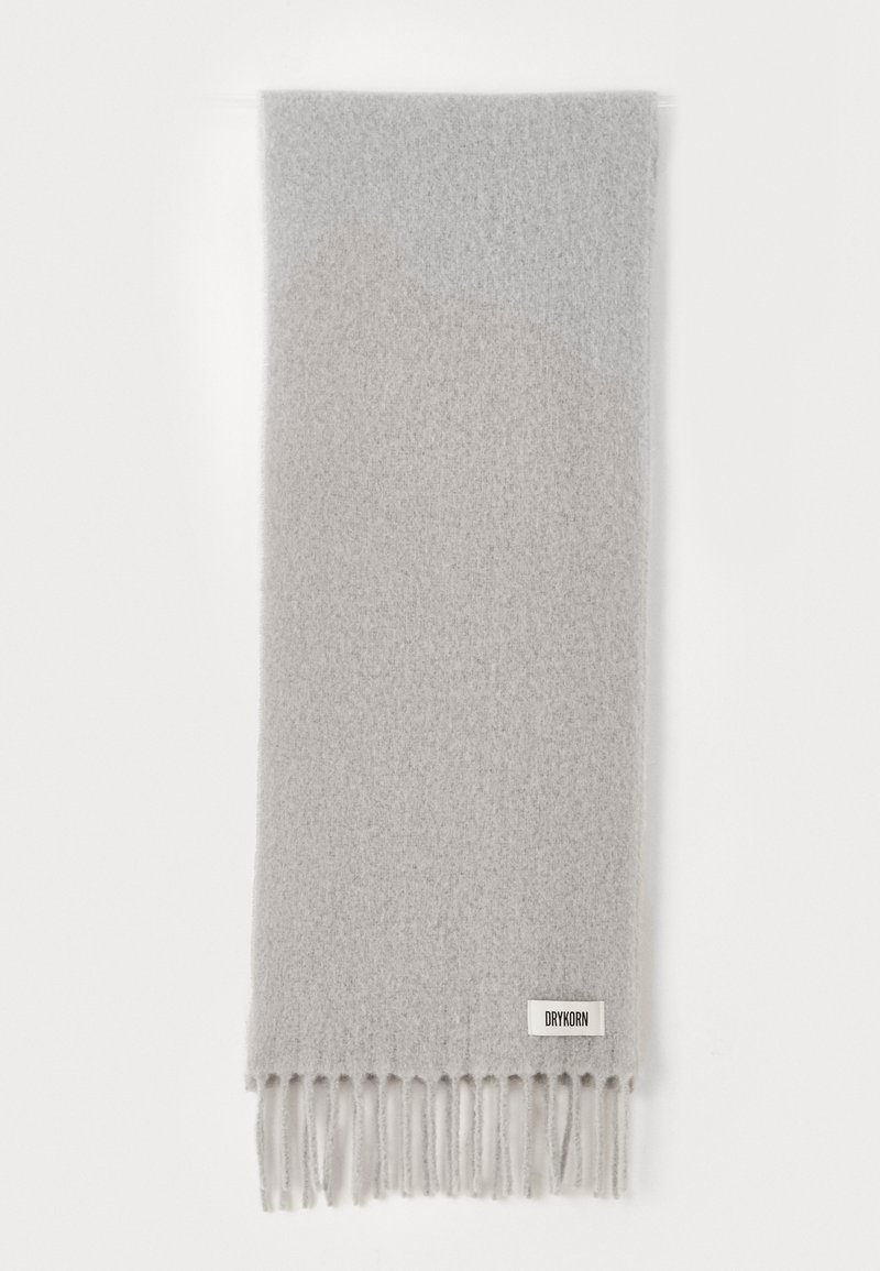 Écharpe en laine gris clair avec un design dégradé et des extrémités frangées. Étiquette cousue en texte foncé, surface en tissu texturé.