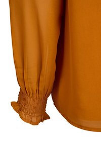 Langärmlige Bluse aus brennorangenem Stoff, mit einem gerafften Bündchen mit Rüschendetail und glatter Textur.