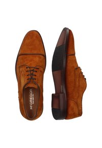 Chaussures habillées en suède marron avec un bout pointu, un design à lacets et une semelle sombre contrastante. Accents de couture notables sur le dessus.