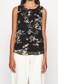 Haut sans manches noir avec imprimé floral blanc et vert ; léger, coupe ample ; encolure ronde ; tissu transparent et détail d'ourlet.