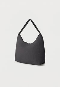 Μαύρη τσάντα ώμου από υφασμάτινη ύλη με υφή, με έναν ενιαίο ιμάντα και επάνω κλείσιμο με φερμουάρ, εμφανιζόμενη σε απλό λευκό φόντο.