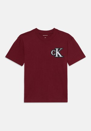 Burgundy cotton t-shirt with short sleeves, crew neckline, featuring a black and white embroidered "ck" logo on the left chest.