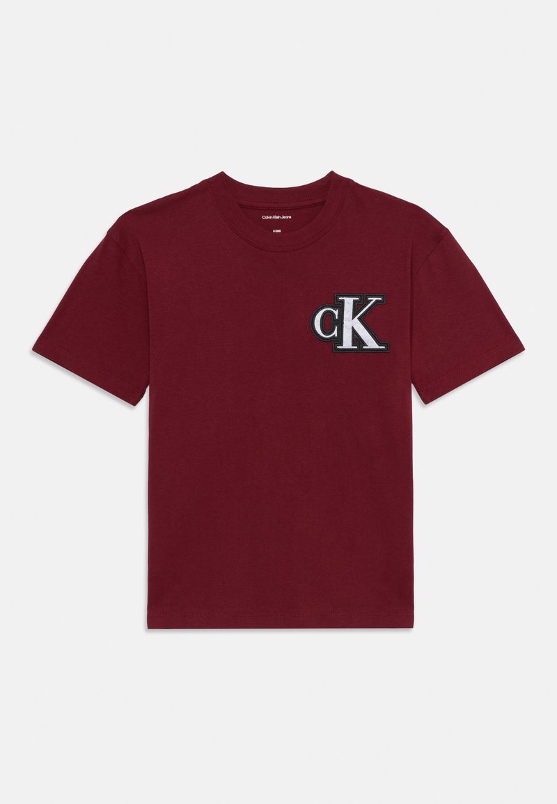 Burgundy cotton t-shirt with short sleeves, crew neckline, featuring a black and white embroidered "ck" logo on the left chest.