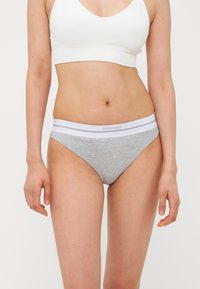 Sous-vêtements en bikini en coton gris avec une ceinture élastique blanche. La ceinture présente un branding subtil et est lisse au touché.