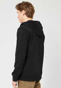 Schwarzer Kapuzenpullover mit weicher Textur, langen Ärmeln und gerippten Bündchen, mit einem schlichten Design und ohne sichtbare Logos oder Muster.