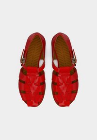 Sandales tissées rouges et brillantes avec un design ouvert, dotées d'une bride à boucle et de semelles texturées, offrant un confort respirant.