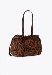 Sac à main en tissu imprimé léopard avec une texture douce, couleurs marron et noir, fermeture à cordon, et deux bretelles noires pour l'épaule.