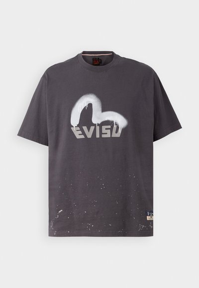 Camiseta gris de manga corta hecha de algodón, con un logo blanco rociado y detalles de salpicaduras de pintura cerca del dobladillo, con cuello redondo.