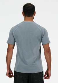 Maglietta sportiva a maniche corte di colore grigio chiaro, dotata di pannelli in rete testurizzata e design aderente, con dettagli di cucitura a contrasto lungo le cuciture.