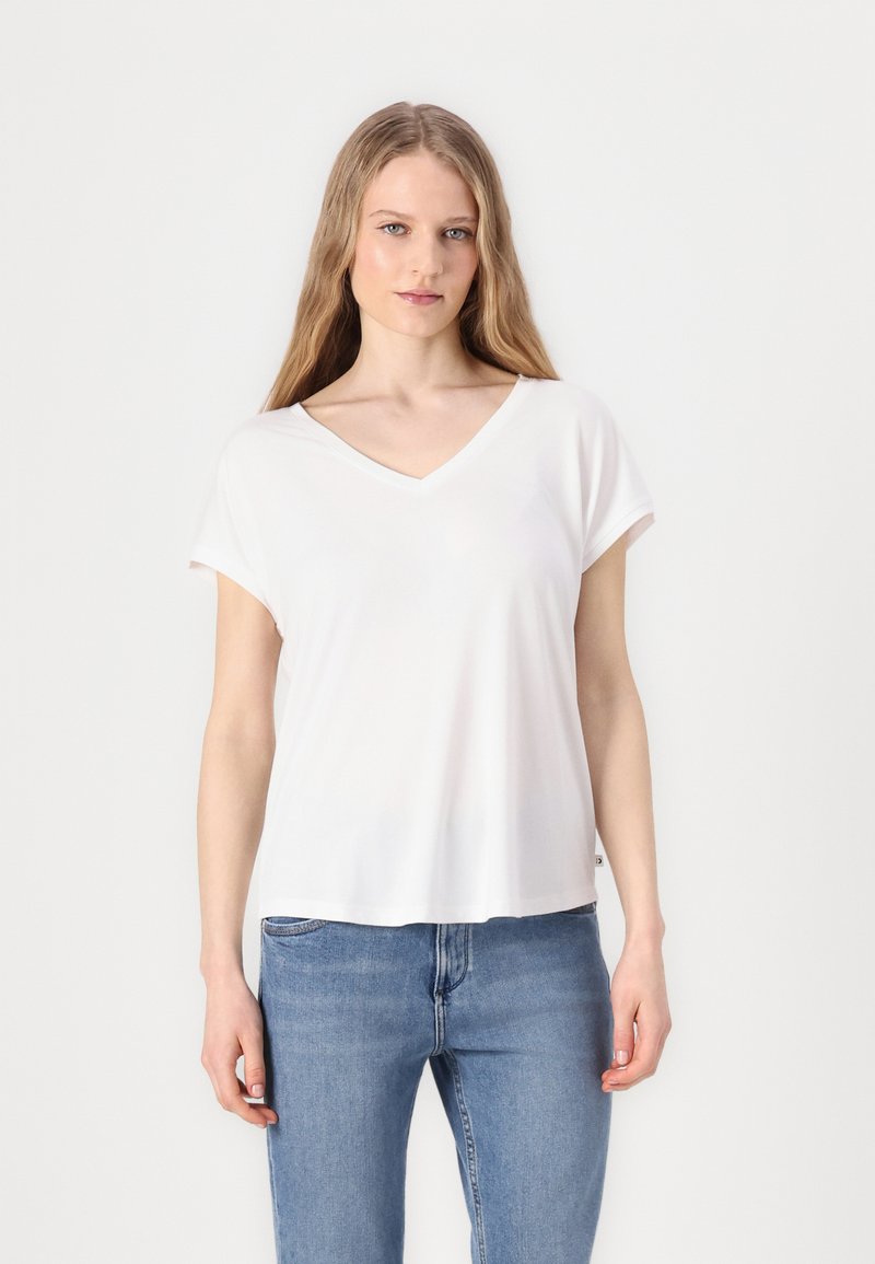 Hvit V-hals T-skjorte i lett, glatt stoff med korte ermer, som har en avslappet passform og diskret detalj på sidesømmene. Kombinert med blå jeans.